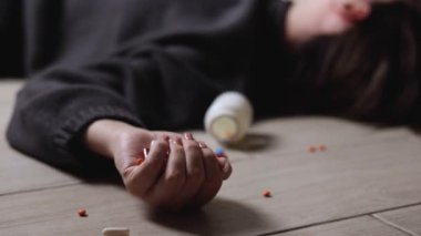 Halıya dağılmış haplarla potansiyel bir aşırı dozu tasvir eden dramatik bir sahne umutsuzluğu simgeliyor.