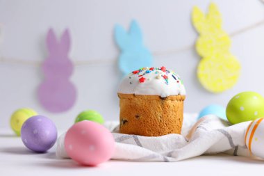 An Easter cake is adorned with icing, decorations, colored eggs, and lit candles, creating a festive atmosphere