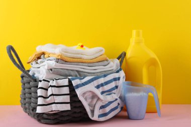 Katlanmış giysiler, plastik ördek ve pastel arka planda deterjan içeren şirin bebek çamaşırları sahnesi..