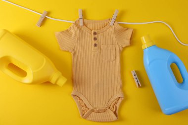 Sevimli sarı bebek tulumu çamaşır deterjanı ve bebek bakımı için ideal oyuncakla asılı.