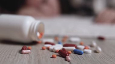 Halıya dağılmış haplarla potansiyel bir aşırı dozu tasvir eden dramatik bir sahne umutsuzluğu simgeliyor.