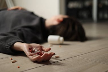 Halıya dağılmış haplarla potansiyel bir aşırı dozu tasvir eden dramatik bir sahne umutsuzluğu simgeliyor.
