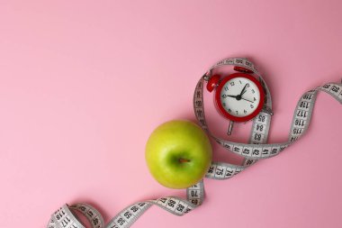 Canlı yeşil bir elma, parlak bir su arka planına karşı bir mezura üzerinde oturur, bu da sağlığı simgeler..