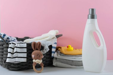 Katlanmış giysiler, plastik ördek ve pastel arka planda deterjan içeren şirin bebek çamaşırları sahnesi..