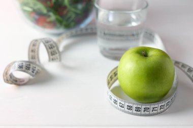 Renkli bir salatanın yanındaki yeşil elma dengeli bir yaşam tarzı için sağlıklı beslenme ve beslenmeyi somutlaştırır.