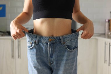 Gevşek kotlara uyum sağlamayı sevinçle kutlayan biriyle ilham verici ve muzaffer bir kilo verme hikayesi gösteriliyor.