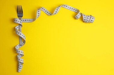 Canlı bir arkaplanda ölçüm bandıyla sarılmış bir çatalın yer aldığı eşsiz bir kompozisyon..