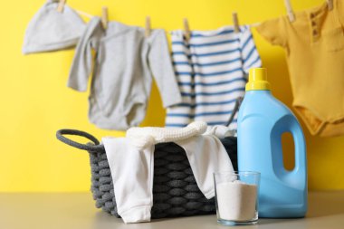 Katlanmış giysiler, plastik ördek ve pastel arka planda deterjan içeren şirin bebek çamaşırları sahnesi..