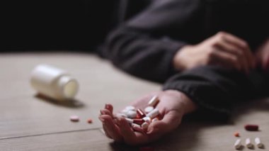 Halıya dağılmış haplarla potansiyel bir aşırı dozu tasvir eden dramatik bir sahne umutsuzluğu simgeliyor.