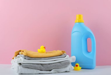 Katlanmış giysiler, plastik ördek ve pastel arka planda deterjan içeren şirin bebek çamaşırları sahnesi..
