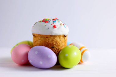 An Easter cake is adorned with icing, decorations, colored eggs, and lit candles, creating a festive atmosphere