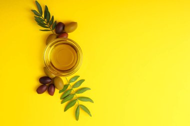 Bu canlı zeytinyağı parlak sarı bir zemin karşısında zeytin ve yeşillikle güzelce sunuluyor.