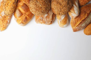 Canlı bir arkaplanda güzel bir şekilde sergilenen çeşitli taze pişmiş ekmeklerden oluşan hoş bir koleksiyon.