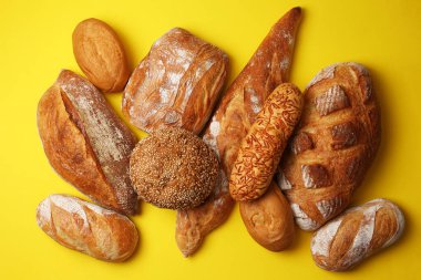 Canlı bir arkaplanda güzel bir şekilde sergilenen çeşitli taze pişmiş ekmeklerden oluşan hoş bir koleksiyon.