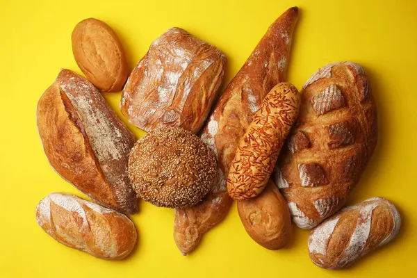 Canlı bir arkaplanda güzel bir şekilde sergilenen çeşitli taze pişmiş ekmeklerden oluşan hoş bir koleksiyon.