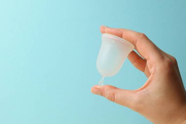 Çevre dostu regl bardağı. Parlak arka planda, kadınların ellerinde. Yüksek kalite fotoğraf