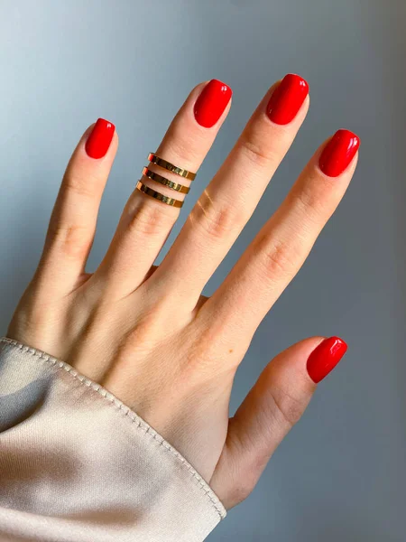 Beautiful nails manicure photo. Red color top nail polish. Female hand, rings, closeup photo, aesthetics. Manicure design, square nail shape. Luxury style, Creative beauty photo, Woman hand. High