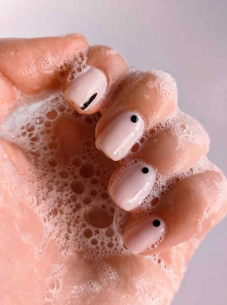 Soap foam manicure nails hand. Beautiful nails manicure photo. Nude top nail polish. Female hand, closeup photo, cleaning hands. Manicure design, square nail shape. Creative beauty photo, hand washing