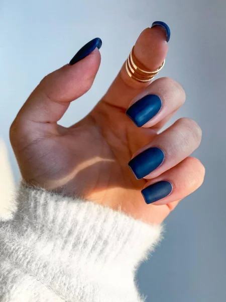 Beautiful nails manicure photo. Dark blue color matte top nail polish. Female hand, rings, closeup photo, aesthetics. Manicure design, square nail shape.Luxury style, Creative beauty photo. Woman hand