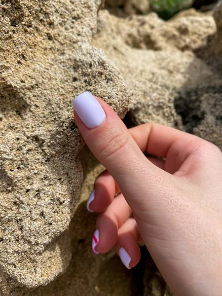 Mağara arka planında açık pembe manikürlü kadın el tırnakları kare şeklinde tırnaklar. Yüksek kalite fotoğraf