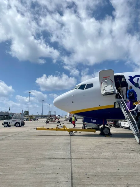 Yolcular uçağa binmek için merdivenleri çıkıyorlar. Gerçekçi, mavi bulutlar altında uçak burun manzaralı. Yüksek kalite fotoğraf