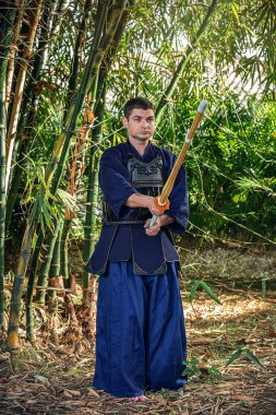 Ormanda bambu kılıçlı geleneksel kendo üniformalı adam.