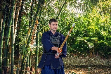 Ormanda bambu kılıçlı geleneksel kendo üniformalı adam.