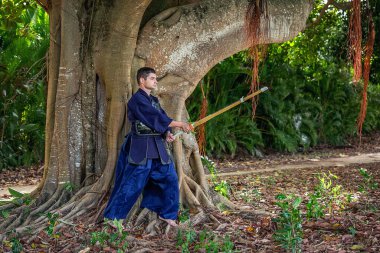 Ormanda bambu kılıçlı geleneksel kendo üniformalı adam.