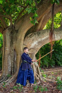 Ormanda bambu kılıçlı geleneksel kendo üniformalı adam.