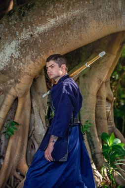 Ormanda bambu kılıçlı geleneksel kendo üniformalı adam.