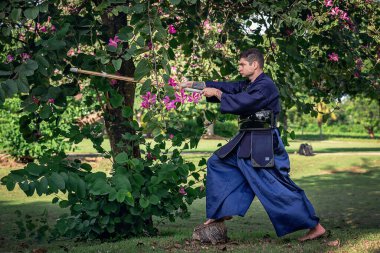 Ormanda bambu kılıçlı geleneksel kendo üniformalı adam.