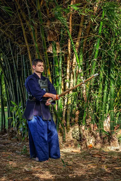 Ormanda bambu kılıçlı geleneksel kendo üniformalı adam.