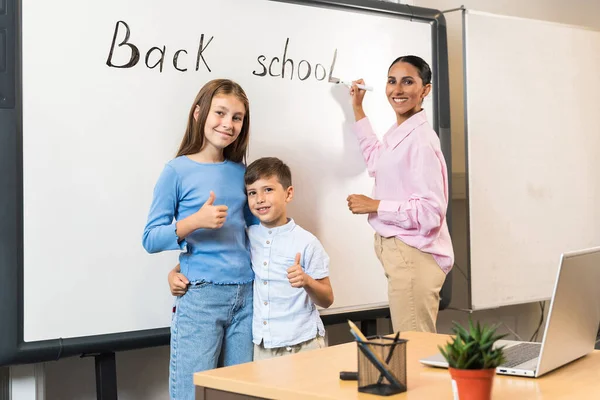 学習の始まりについての概念 子供と教師はブラックボードの近くに立って 学年の初めに喜んでいます 現代の教室 生徒と先生がレッスンを始める — ストック写真