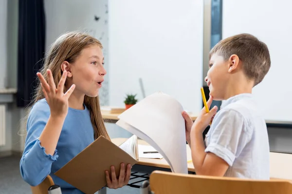 Élénk Beszélgetés Gyerekekről Osztályteremben Egy Iskoláslány Elmagyarázza Asztaltársának Hogyan Írják — Stock Fotó