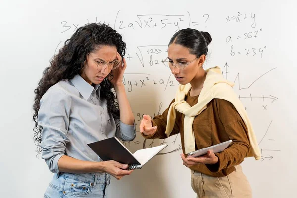 かわいい東洋の少女が問題を解決する 学生は ノートブックを見て 数学の方程式を理解していません 高等学校の女子生徒が黒板の近くに立っている — ストック写真