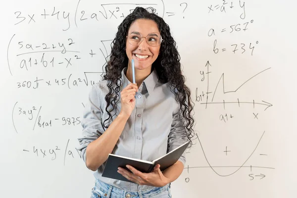 夢の仕事を考えながらクラスで勉強しているアラビアの女性学生の笑顔の肖像画 女の子は方程式とグラフを持つ数学的なボードを立っています 手札とペンを握る — ストック写真