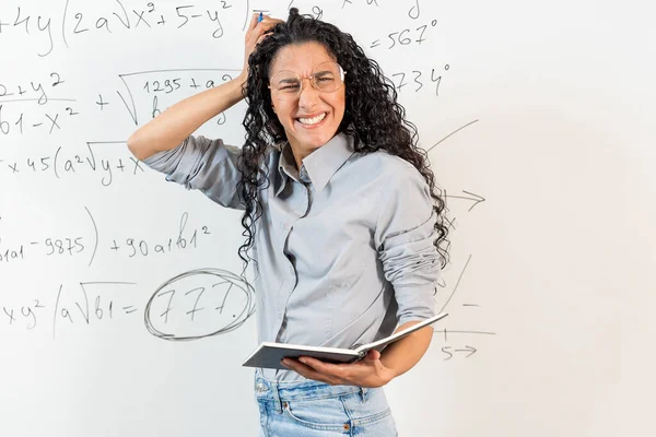 中東の女性学生の肖像画は強調し チャグリン 頭を抱えている女性は 不安と誤解を表しています 背景は数学方程式を持つブラックボードです — ストック写真
