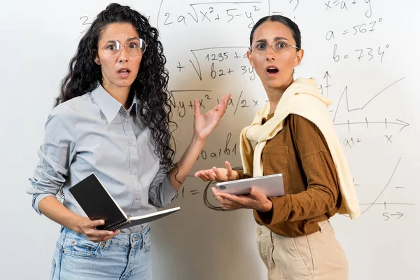 Zwei Verwirrte Studentinnen Lateinischen Aussehens Stehen Neben Der Tafel Und — Stockfoto
