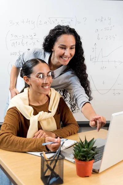 図書館の学生特有の研究について解説します カジュアルに座って机の上に立っている2人の東洋の女性は ノートパソコンを使って モニターを指して話す コンサルティングコンセプト — ストック写真
