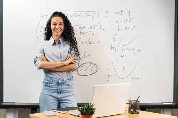 美しい笑顔の東洋の女性教師の肖像画は 交差した腕を持つテーブルの近くの教室に立っています 数学的な計算とグラフを持つホワイトボードの背後にある 学校に戻る — ストック写真