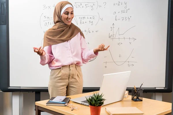 히잡의 교사는 컴퓨터에서 웨비나를 이끌고 있습니다 즐겁게 학생들을 가르치는 자료를 로열티 프리 스톡 사진
