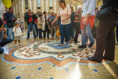 MILAN, İTALYA - 2 Ekim 2015: Milano 'daki Vittorio Emanuele Galerisi' nde, yerde üç kez mozaik boğa testisleri turistler daire çiziyor.