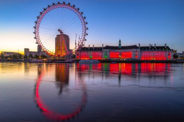 LONDON, ENGLAND - JUNE 26, 2016. London Eye at dawn illuminated in red  clipart