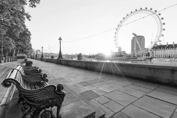 stock image LONDON, UK -  JULY 18,2016. Empty bench and London Eye at sunrise in London, UK