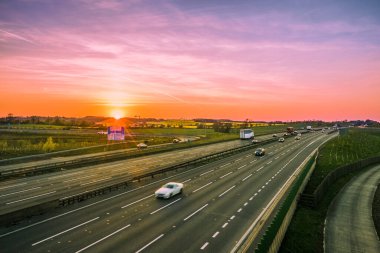 Flitwick kavşağı yakınındaki M1 otoyolunda Birleşik Krallık 'ta bulanık arabalarla renkli gün batımı