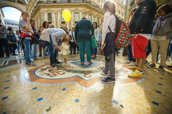 MILAN, İTALYA - 2 Ekim 2015: Milano 'daki Vittorio Emanuele Galerisi' nde, yerde üç kez mozaik boğa testisleri turistler daire çiziyor.