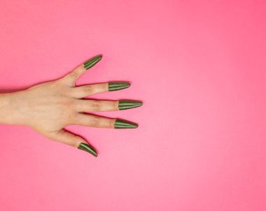 Güzel bir kadın elinin yaratıcı fotoğrafı ve yeşil pittospora yapraklarından yapılmış tırnaklar. Magenta geçmişi. Boşluğu kopyala.