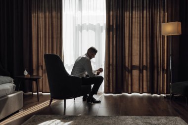 Şık damat elbiselerini giyer, düğün törenine hazırlanır. Sabah ışığında harika bir iç mekan. Damadın sabahı.