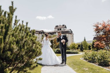 Mutlu karı koca. Düğün günü. Güzel doğa. Fotoğraf çekilirken yürü. Birbirlerine gülümserler. El ele tutuşarak..