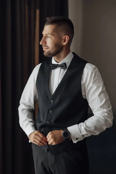 一个穿着黑色西装和领带的时髦新郎的早晨 他在酒店里的准备工作 在一间照相馆里 系着纽扣和夹克 — 图库照片